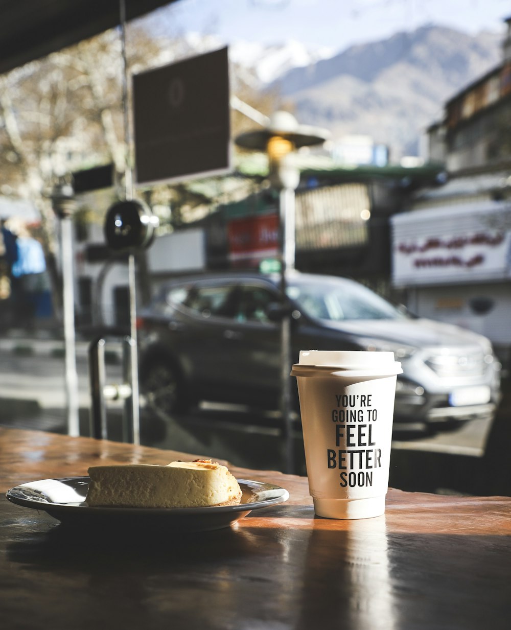 weißer Kunststoff-Kaffeebecher in der Nähe einer weißen Keramikuntertasse mit Gebäck