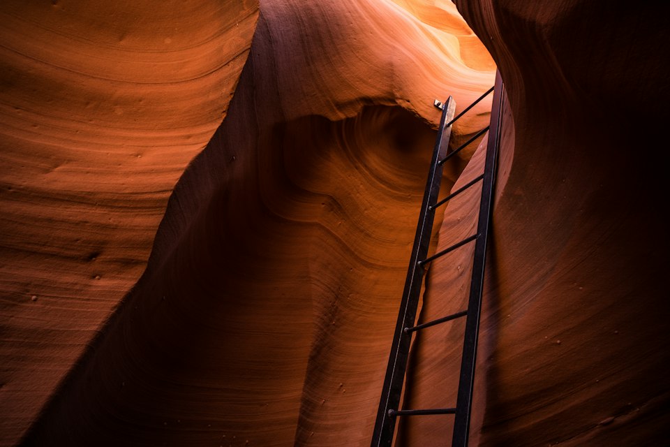 A wooden ladder descending through the narrow, corkscrewing sandstone walls of Lower Antelope Canyon