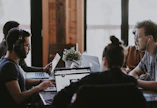selective focus photography of people sits in front of table inside room