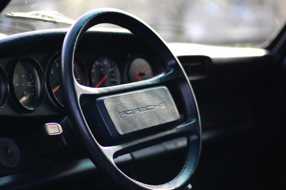 selective focus photography of black Porsche steering wheel