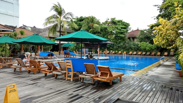A serene poolside area surrounded by lush greenery and sun loungers ready for a peaceful day.