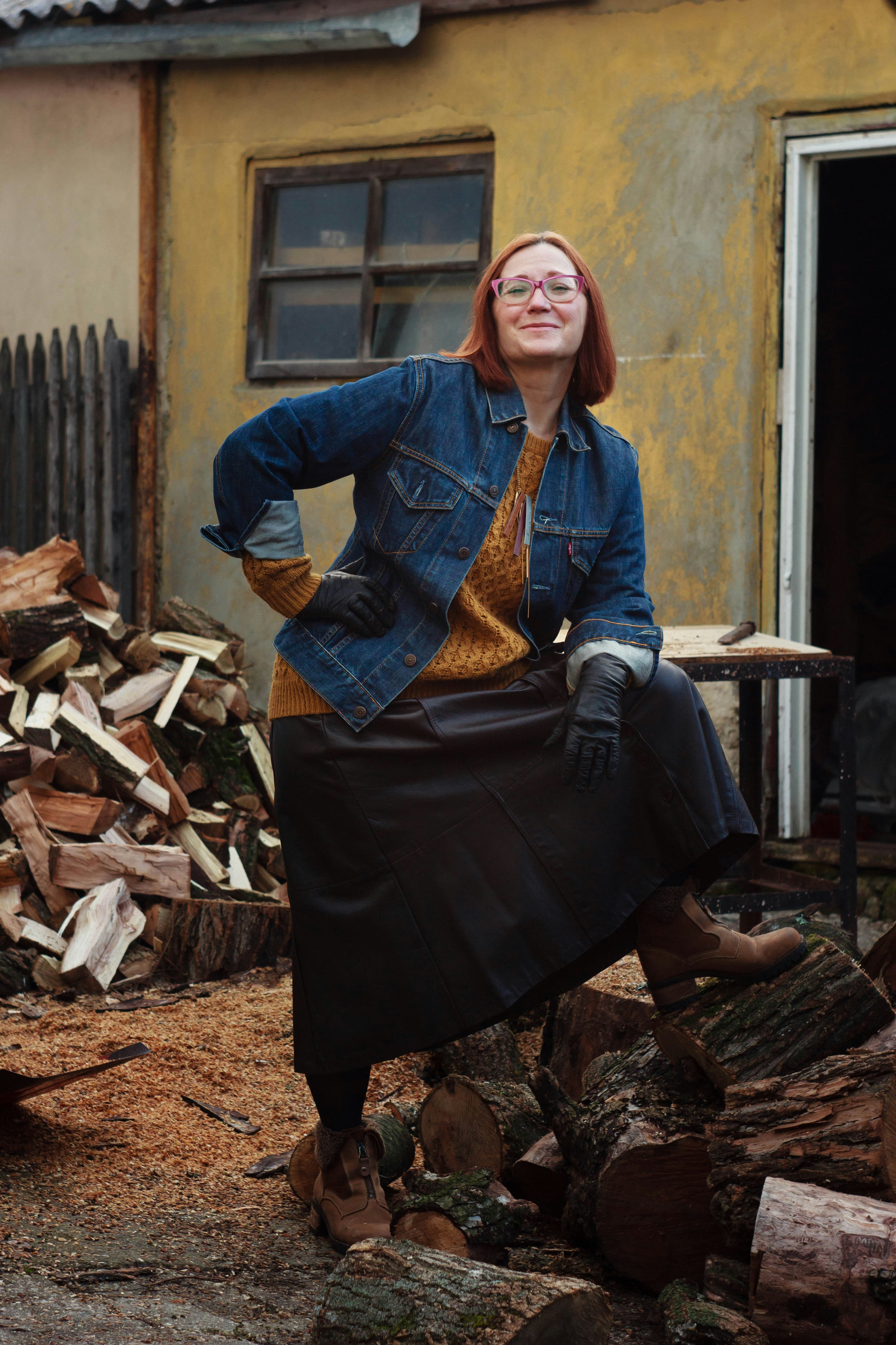 brown haired woman in blue denim jacket standing near firewoods