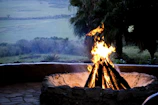 Evening view of the campfire area surrounded by natural stones and soft glowing lights.