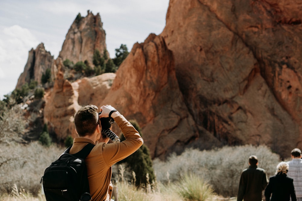 man taking photo of rock formation