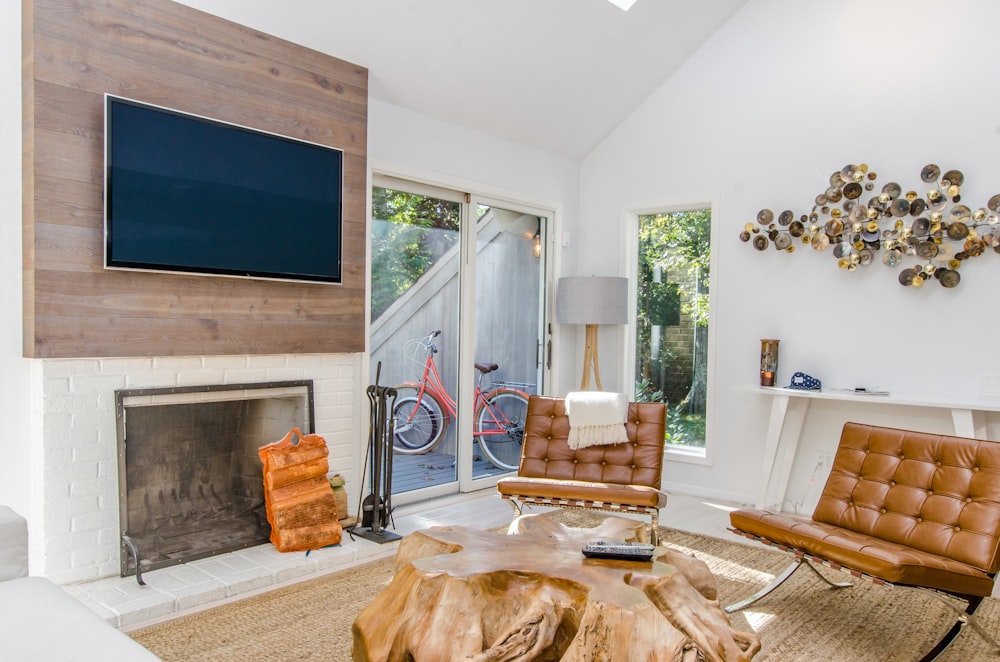 two tufted brown leather chairs in front of brown wood stump center table