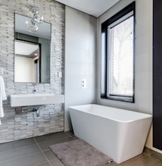 white ceramic bathtub near white framed window