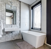 white ceramic bathtub near white framed window