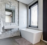 white ceramic bathtub near white framed window