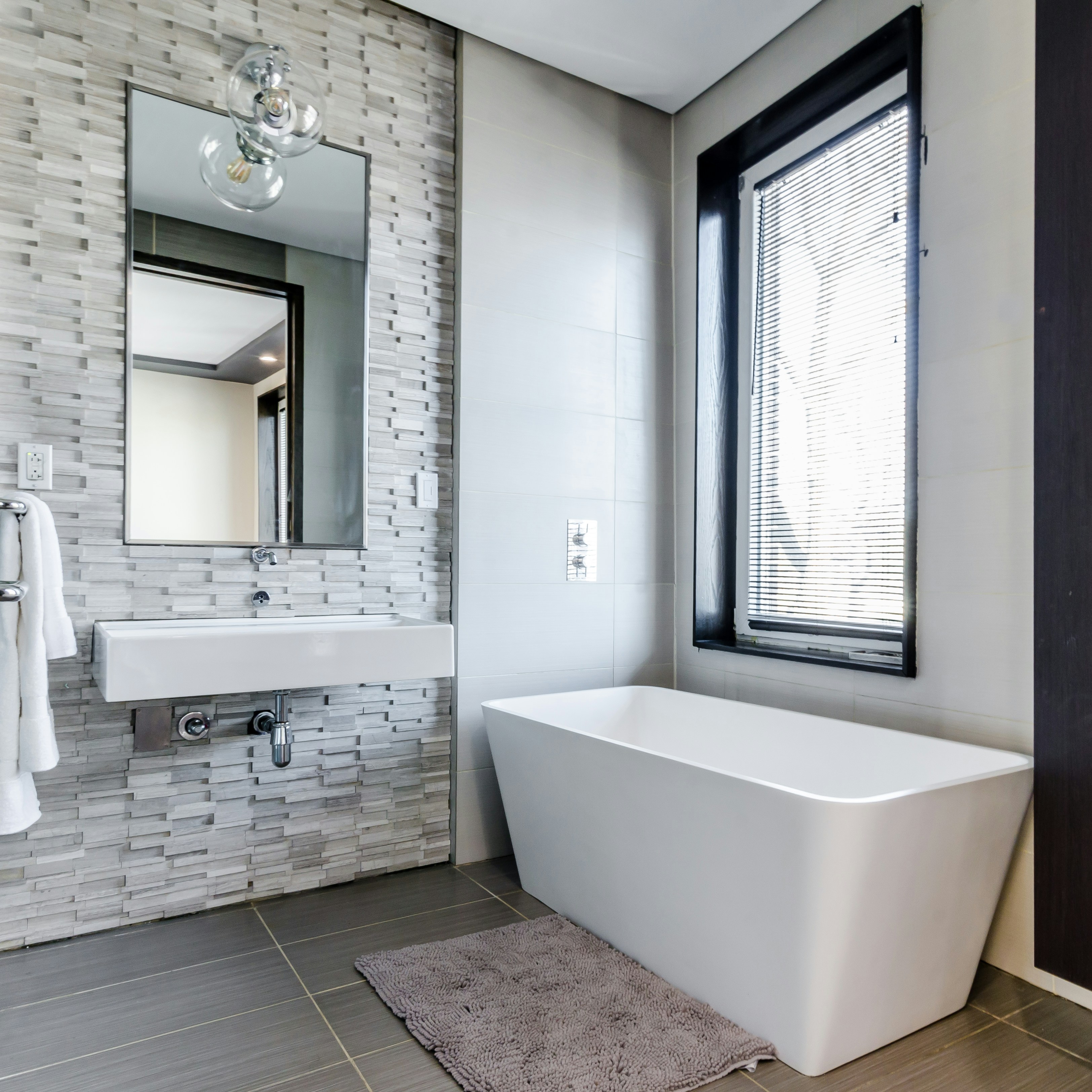 white ceramic bathtub near white framed window