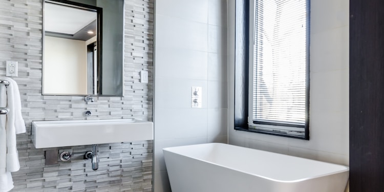 white ceramic bathtub near white framed window