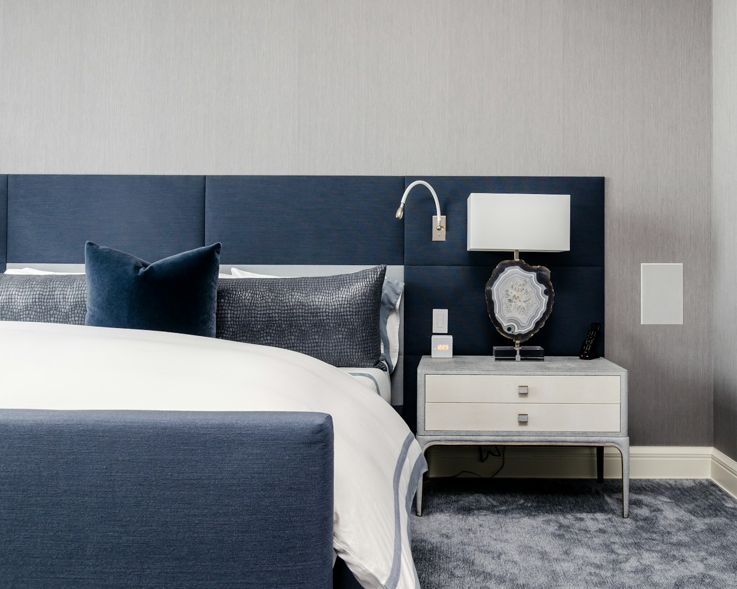 white and clear desk lamp on white wooden nightstand near bed by Chastity Cortijo