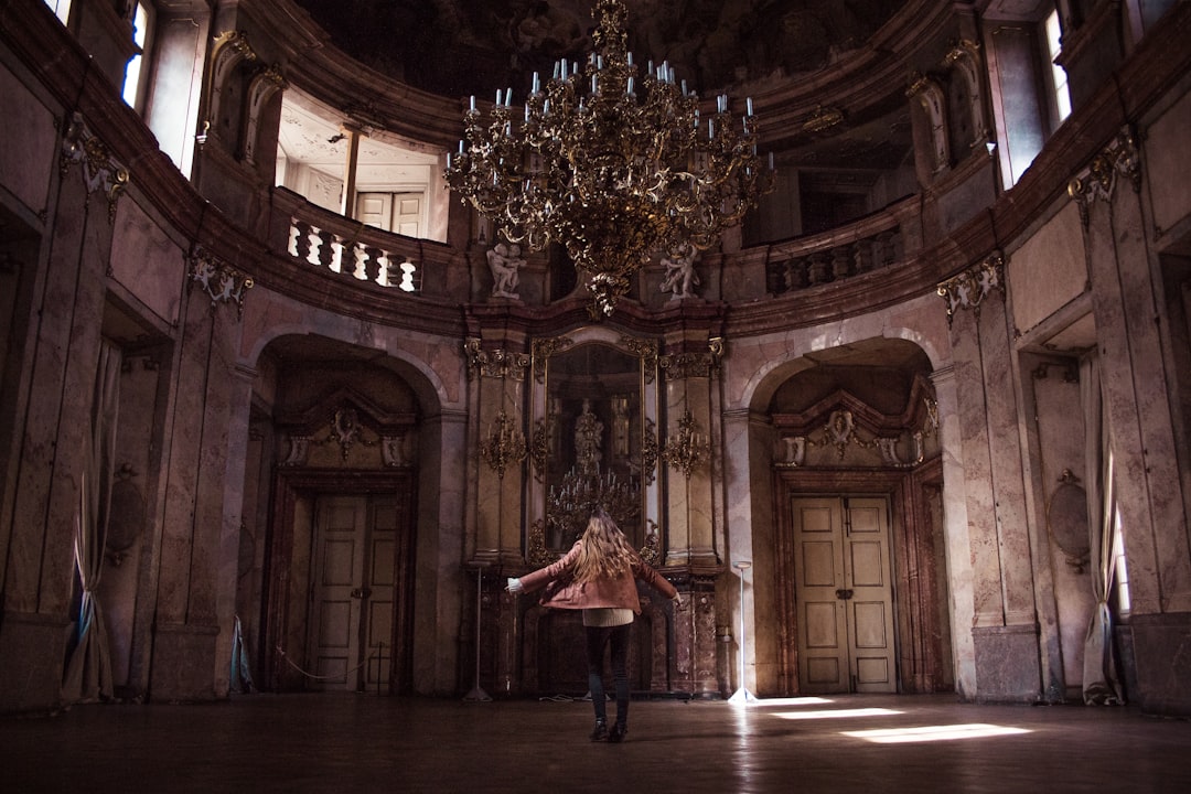 woman standing under gold chandelier indoors