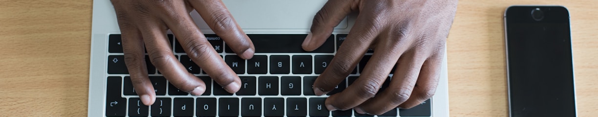 person's hand on MacBook near iPhone flat lay photography