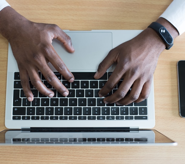 person's hand on MacBook near iPhone flat lay photography