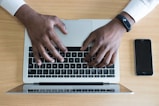 person's hand on MacBook near iPhone flat lay photography