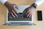 person's hand on MacBook near iPhone flat lay photography