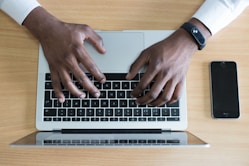 person's hand on MacBook near iPhone flat lay photography