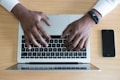 person's hand on MacBook near iPhone flat lay photography
