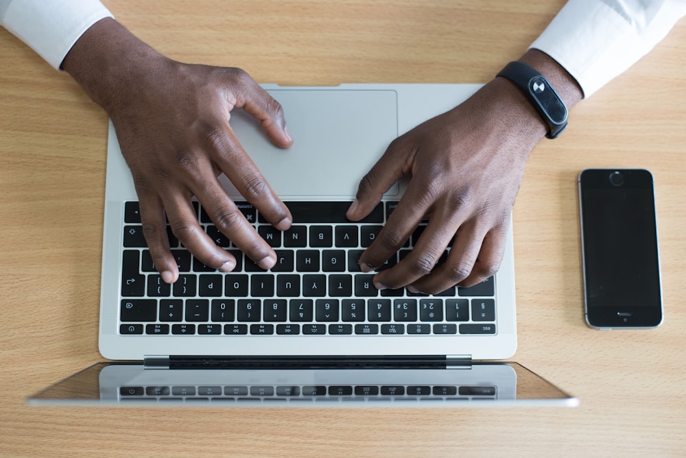 person's hand on MacBook near iPhone flat lay photography