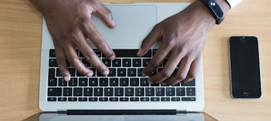 person's hand on MacBook near iPhone flat lay photography