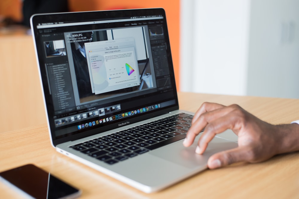 personne utilisant MacBook Pro sur une table en bois marron