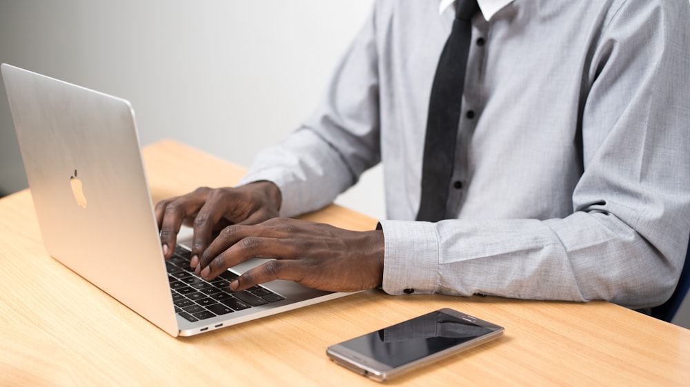 man sits typing on MacBook Air on table