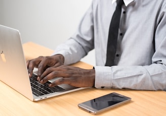 man sits typing on MacBook Air on table