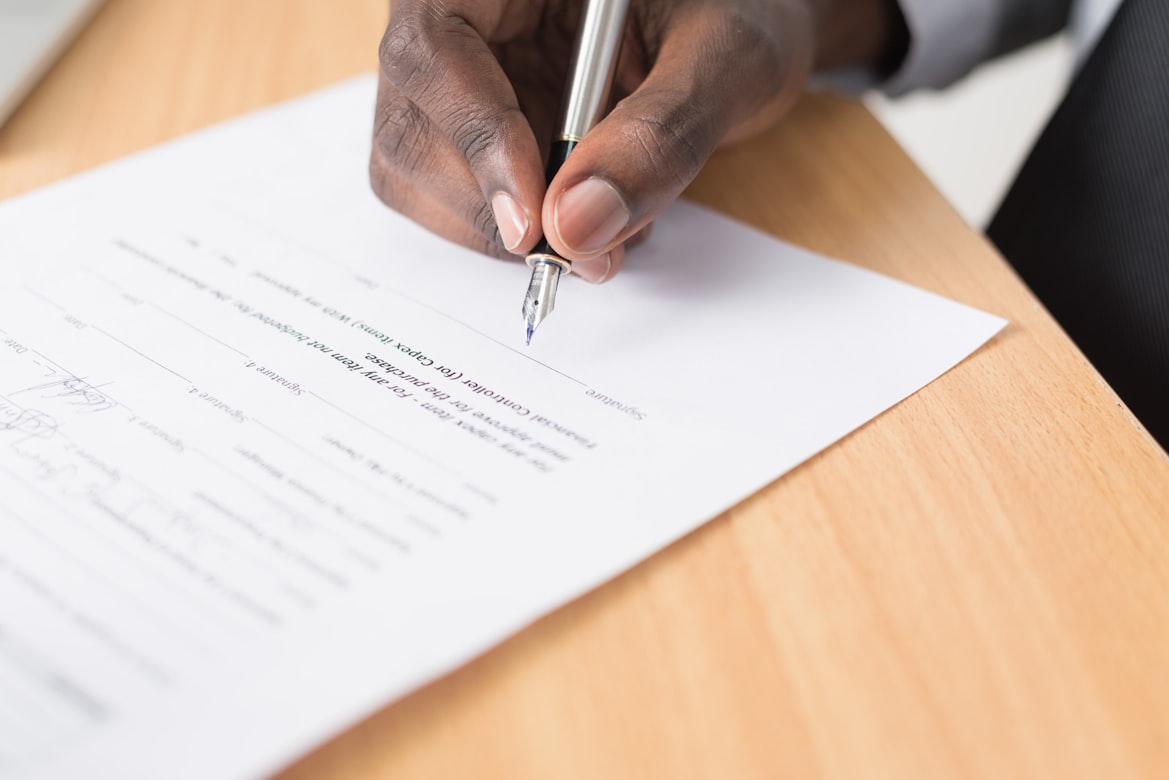 A person holding a pen and signing an agreement.