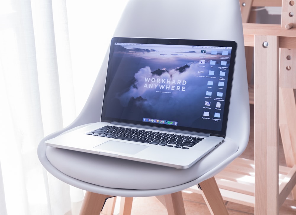 MacBook Pro sur chaise rembourrée blanche