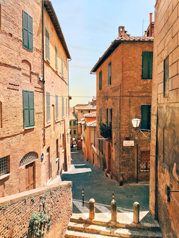 A charming cobblestone street in Florence with historic buildings bathed in warm sunlight.