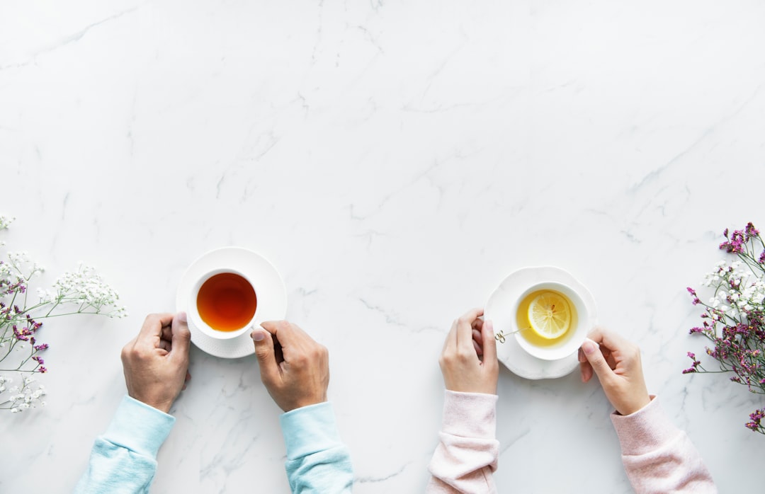 two person holding ceramic mugs