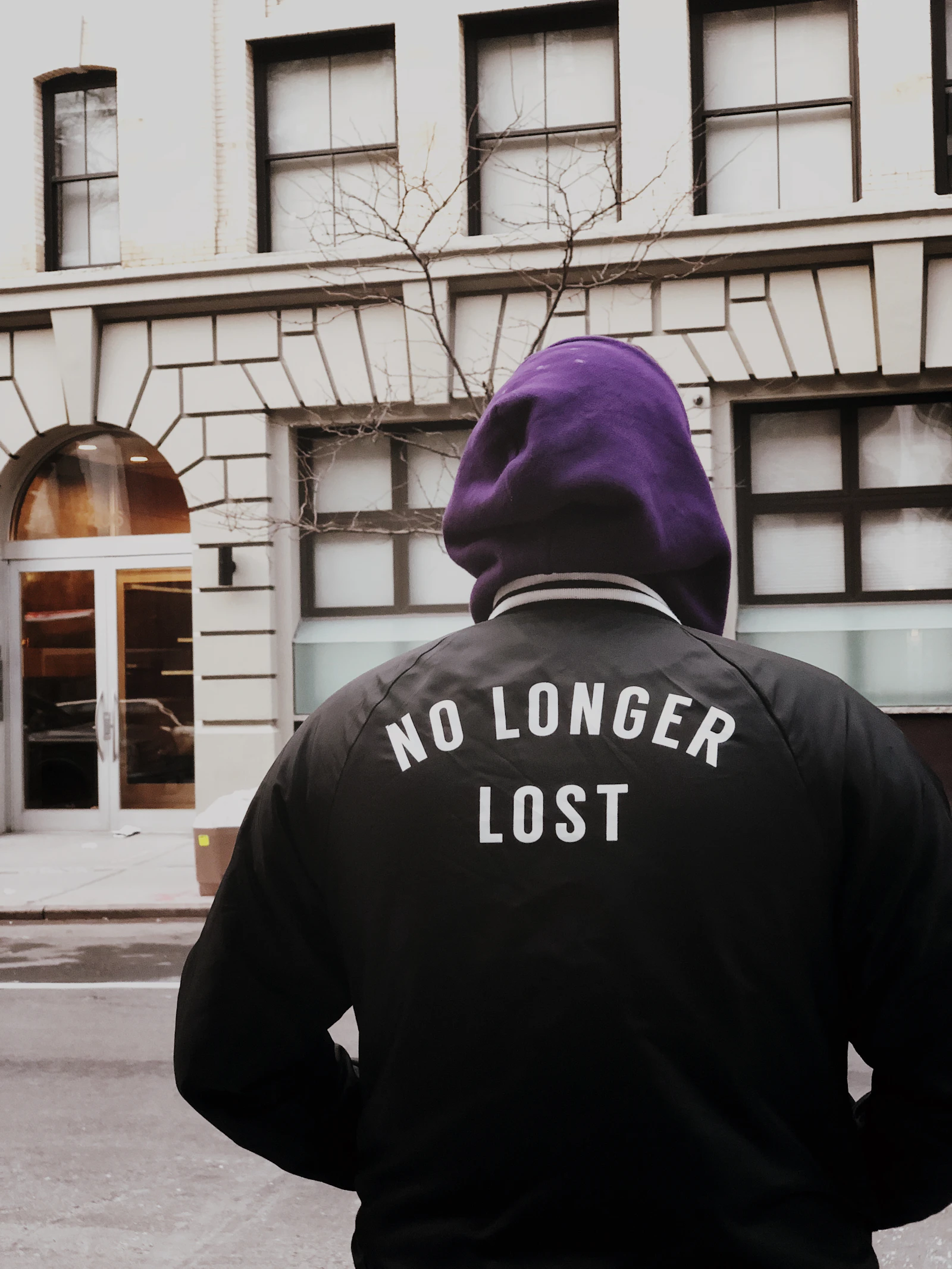 A person in a hoodie walking in the city, suggesting relaxed menswear styling