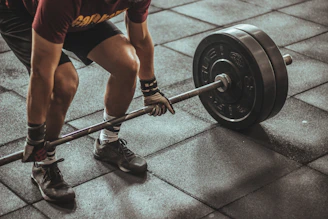A person lifting a heavy barbell from a rubber gym floor