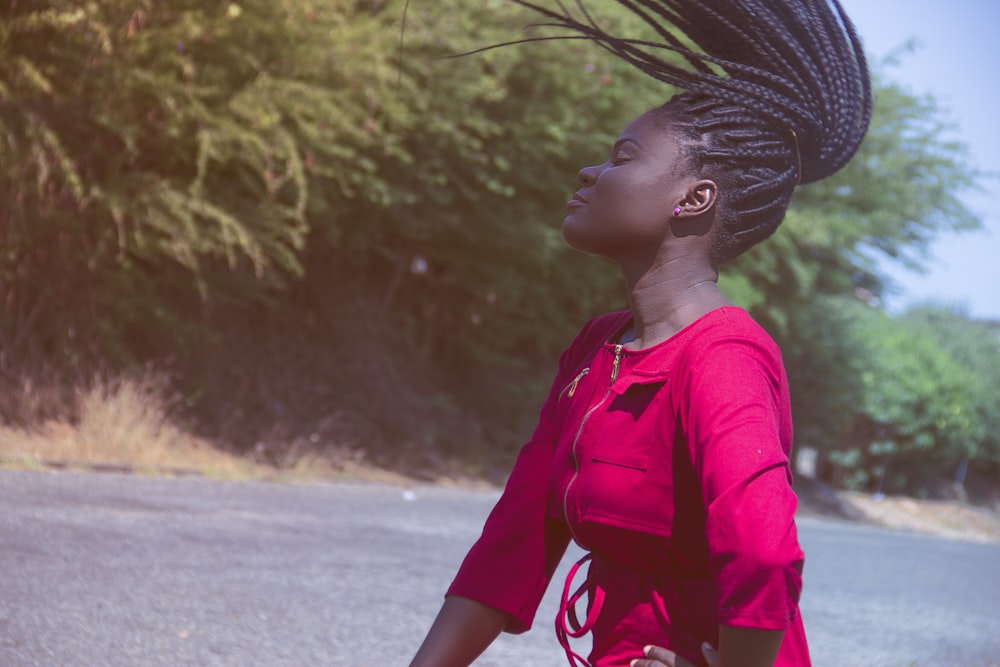 woman waving her hair while standing on road near tree at daytime