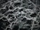 The image displays an intricate pattern of dark green and black marble with white veining. The texture appears smooth and polished, with the veins creating a natural, abstract design across the surface.