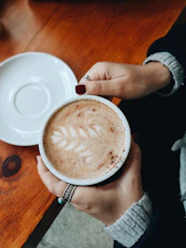 Close-up of freshly manicured hands holding a cup of coffee.