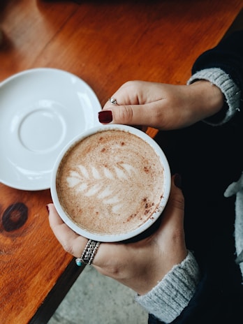 Close-up of hands with perfectly manicured nails holding a cup of coffee