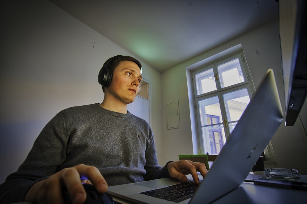 hombre usando MacBook y auriculares inalámbricos