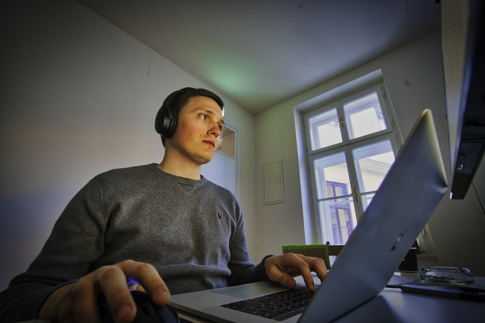 Mann mit MacBook und schnurlosen Kopfhörern