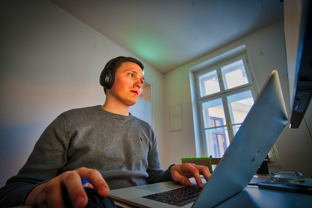 man using MacBook and cordless headphones
