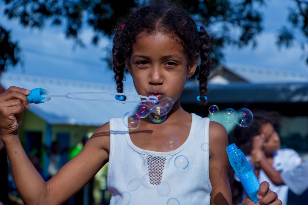 girl in white sleeveless top blowing bubbles