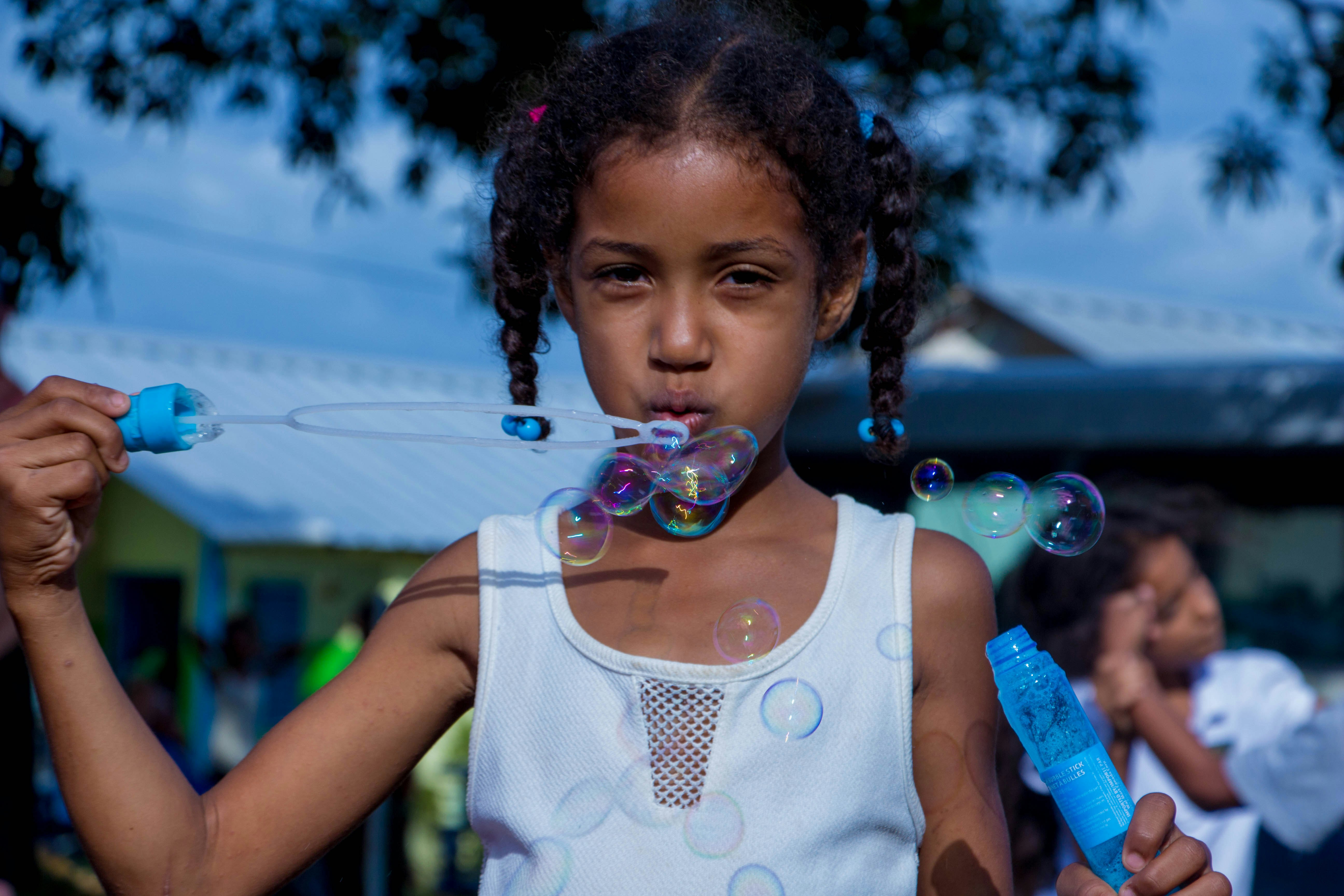 girl in white sleeveless top blowing bubbles