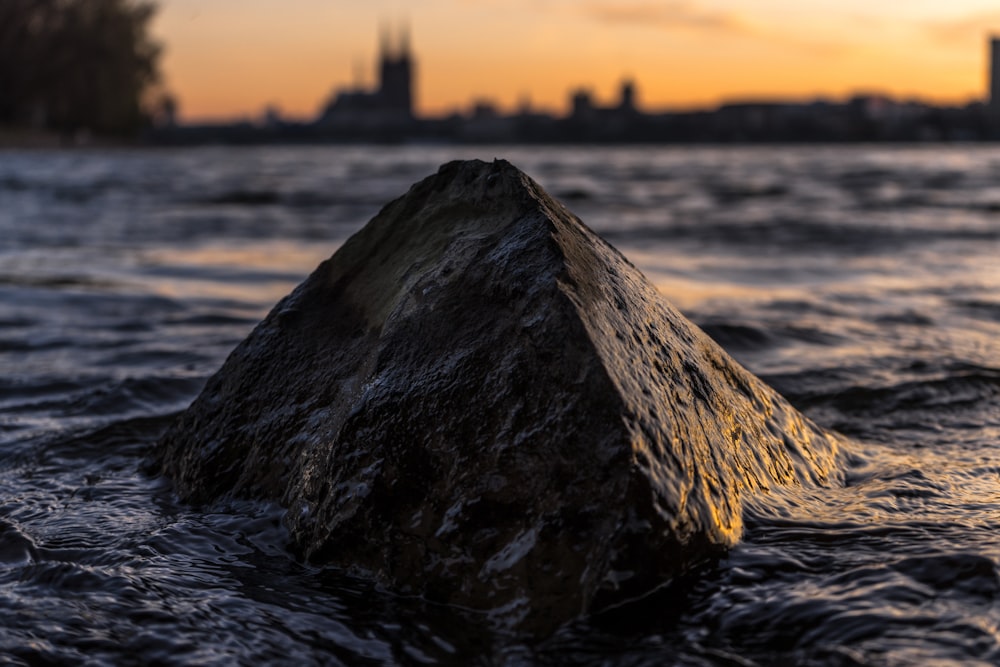 brown rock on body of water at golden hour