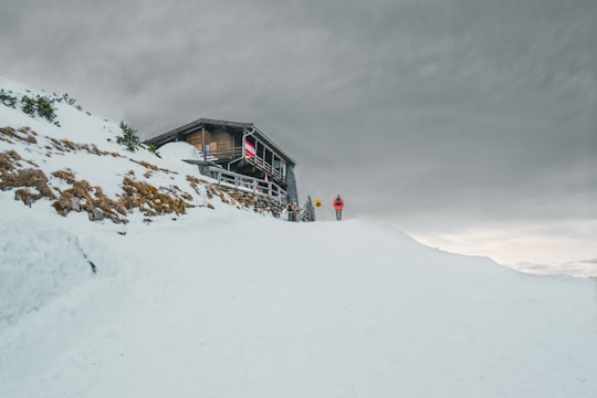 person standing on glacier hill near house under white cloudy skies during winter in Untersberg Germany