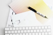 Apple Magic Keyboard, papers, and pen on white surface
