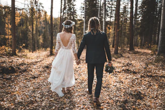 Couple walking hand-in-hand through a sunlit forest during pre-wedding shoot