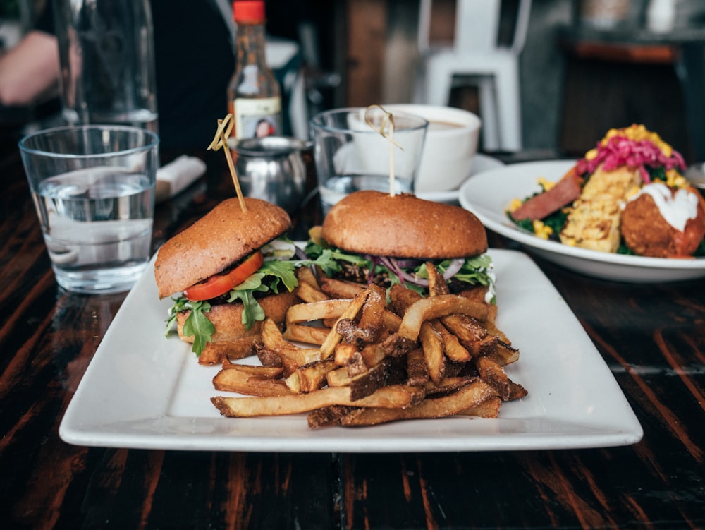 Selektives Fokusfoto von Burgern und Pommes, die auf dem Teller serviert werden