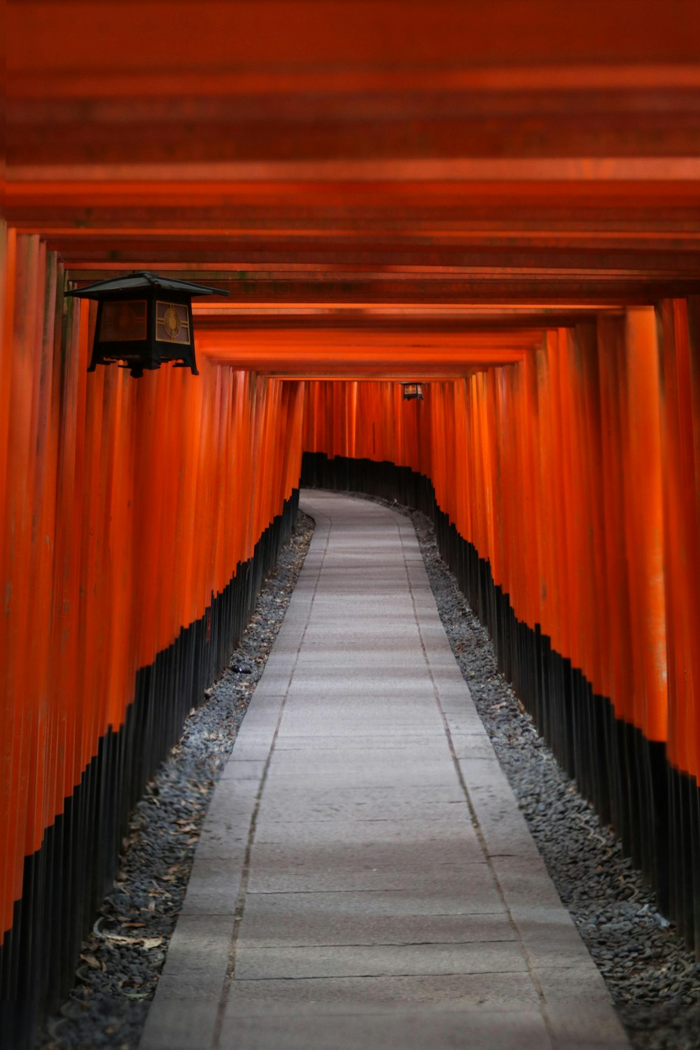 uma passarela ladeada por portões laranjas que levam à distância