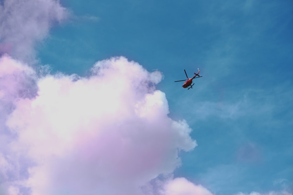 red helicopter on flight about to reach clouds