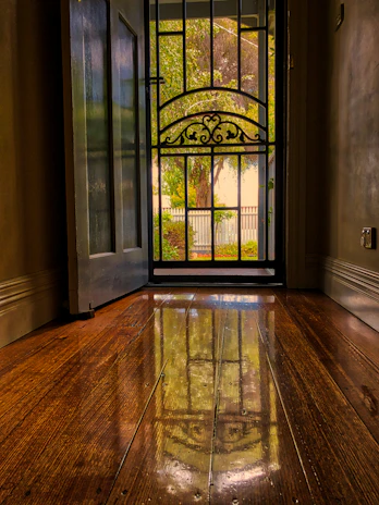 An elegant glass door framed by polished wood, reflecting a sunny garden.